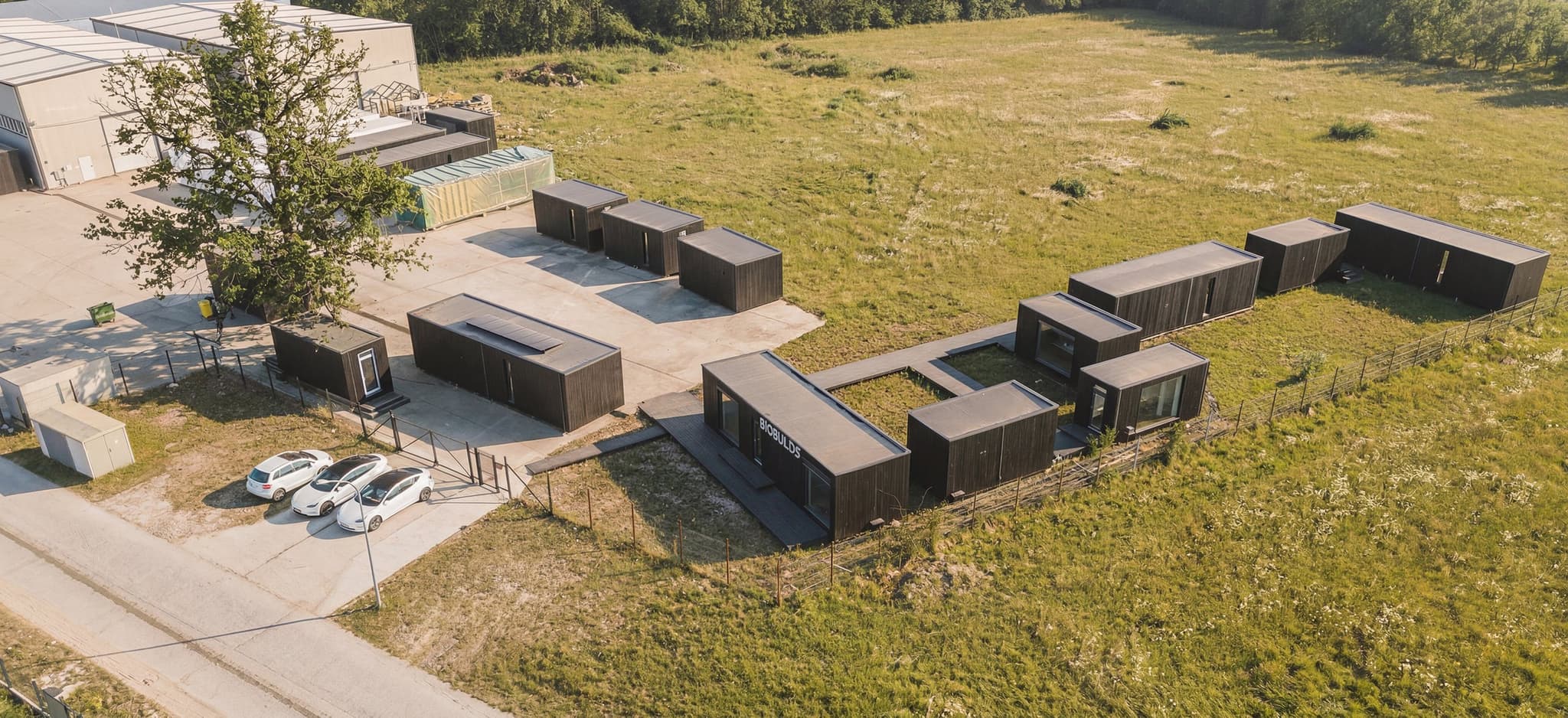 Drohnenaufnahme des BIOBUILDS-Werks in Moreni mit der Produktionshalle und zwei fertiggestellten Häusern auf dem Gelände.