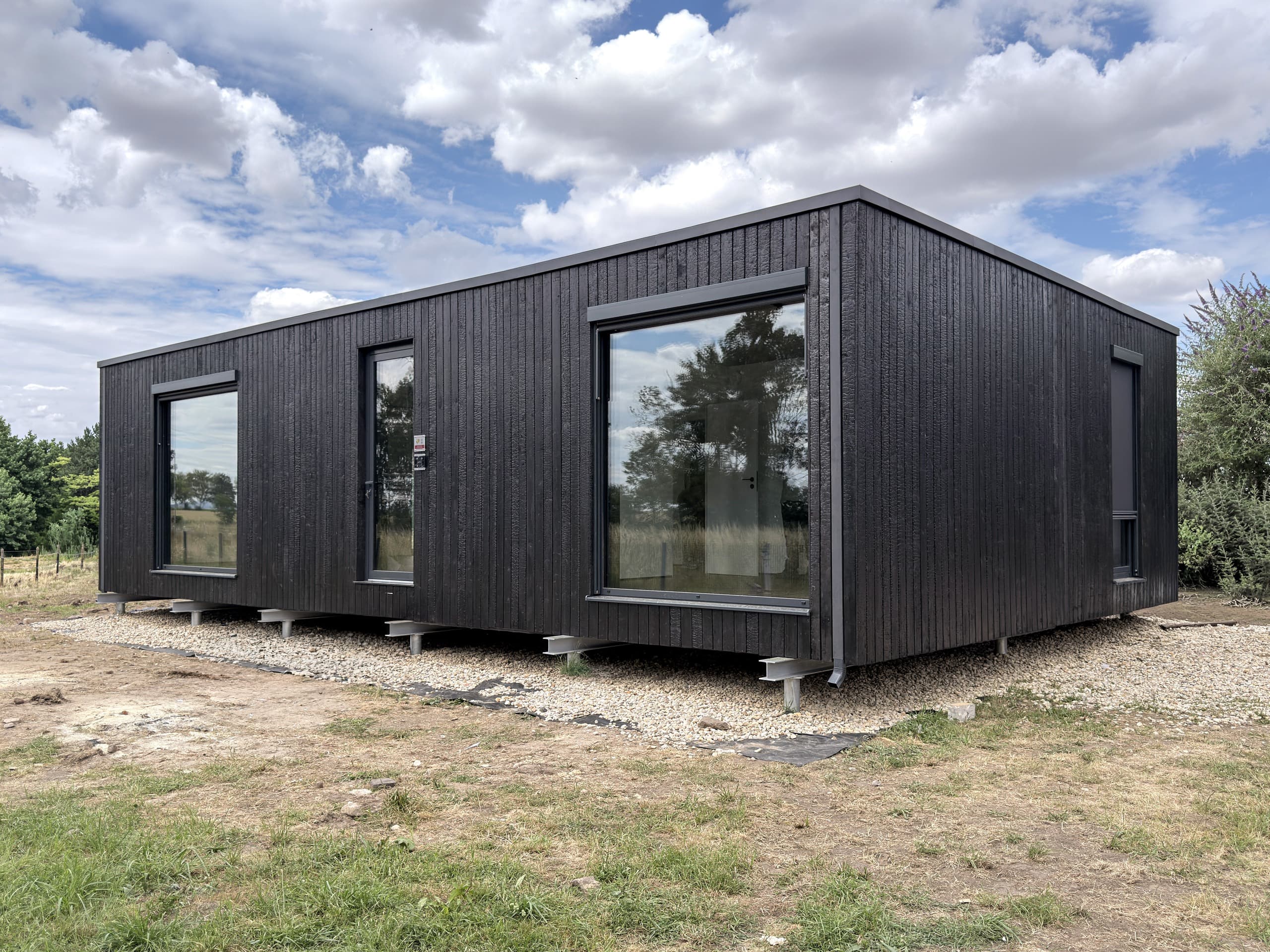 BIOBUILDS-Haus mit Holzverkleidung und großen Fenstern
